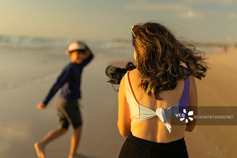 母亲拍摄儿子在海滩上奔跑图片素材