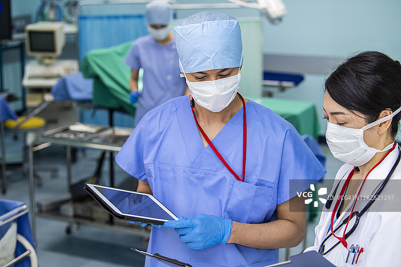 女医生和外科医生检查数字化病人图表图片素材