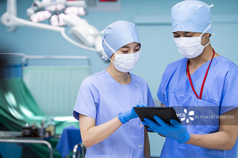 女医生和外科医生在手术室检查病人电子病历图片素材
