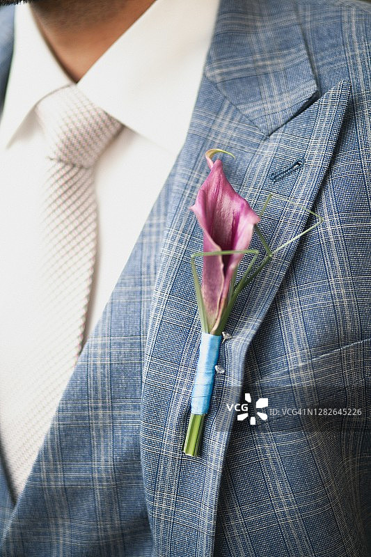 新郎身穿白色衬衫、蓝色西装，佩戴白色襟花，婚礼主题图片素材