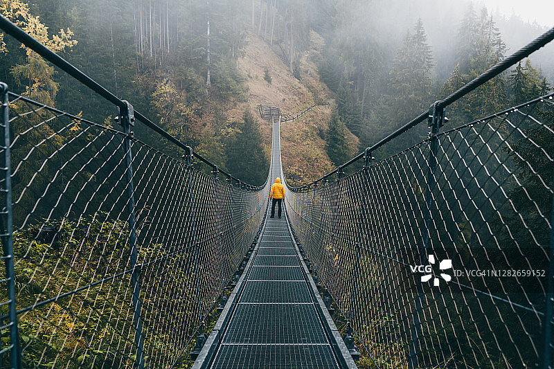 男人站在森林中的悬索桥上图片素材