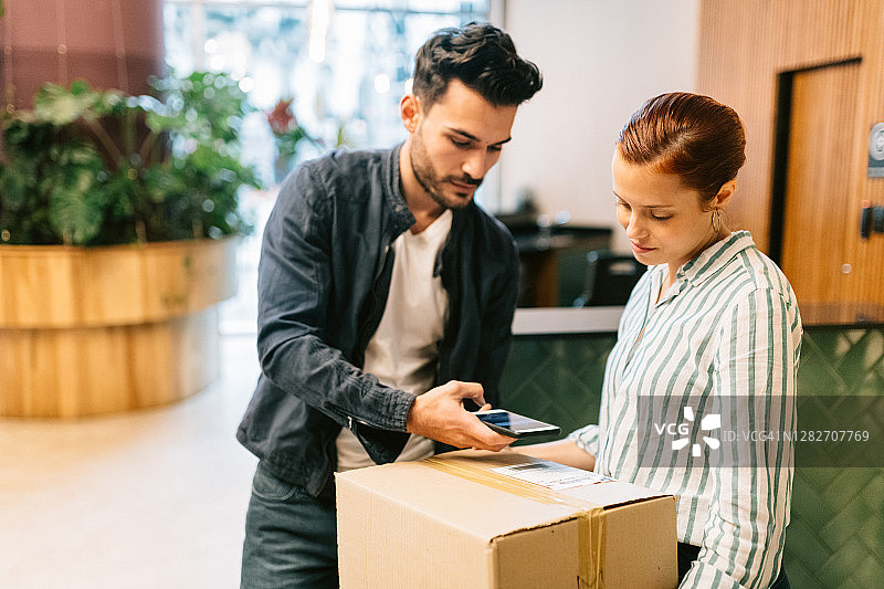快递员在办公室前台扫描包裹图片素材