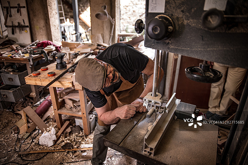 在车间检查电锯的意大利木匠图片素材