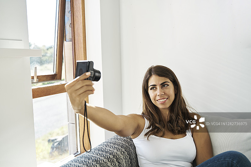 快乐的年轻女子用相机自拍图片素材