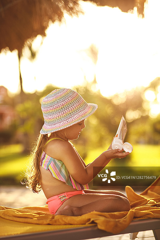 穿着泳衣的小女孩涂抹防晒霜呵护肌肤图片素材