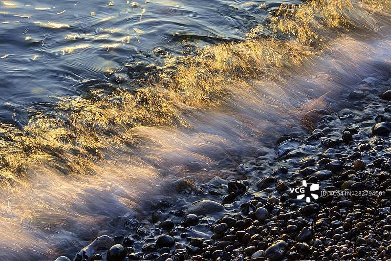 日出时分海滩上的波浪与浪花，波罗的海萨斯尼茨白垩悬崖下的波浪运动图片素材