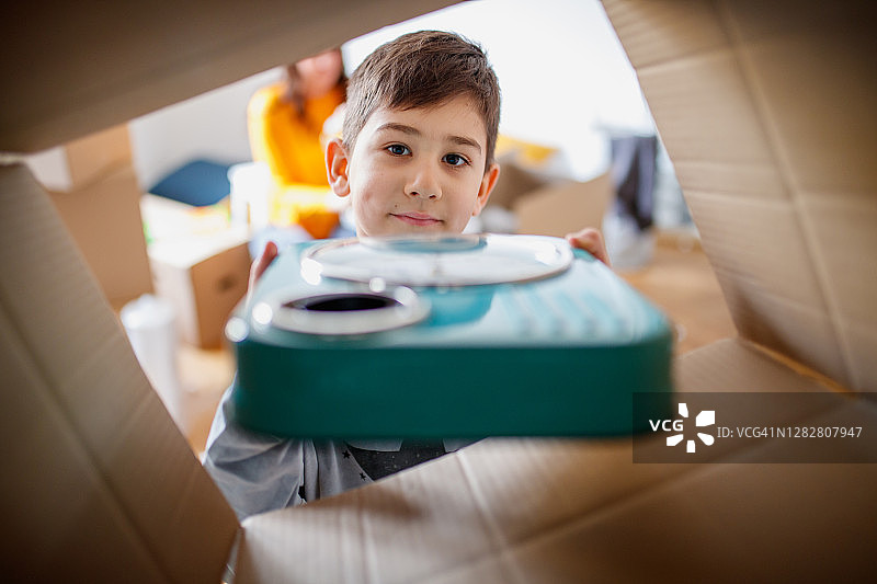 男孩在搬家时把时钟放进盒子里打包图片素材