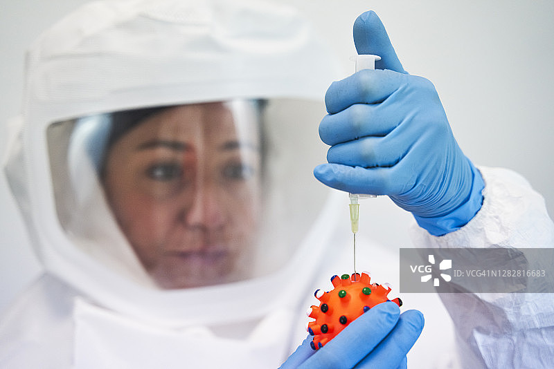 身穿防化服的实验室工作人员注射病毒疫苗，对抗冠状病毒图片素材