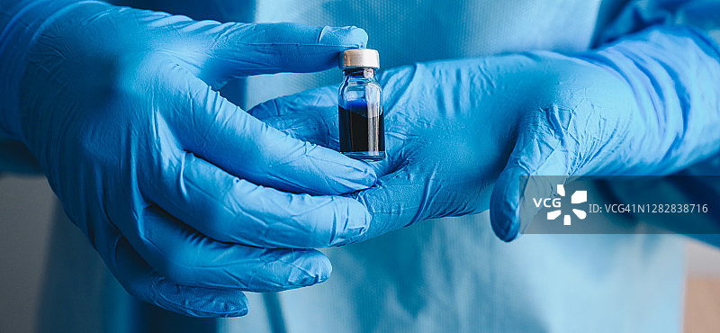 医护人员手持新冠疫苗样本测试瓶的局部照片图片素材