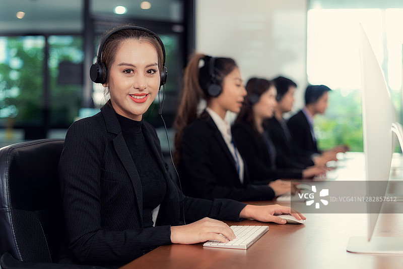 金融顾问呼叫中心客服团队在办公室工作，佩戴耳机，微笑的客服代表，年轻员工在办公室工作，商务团队支持图片素材