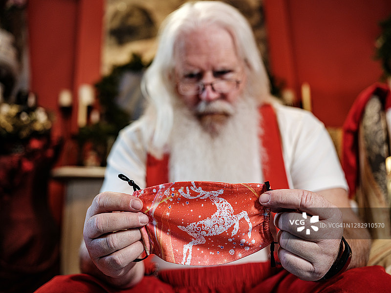 戴着口罩正在穿衣服的圣诞老人图片素材