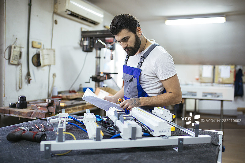 在电路板上工作的英俊工程师图片素材