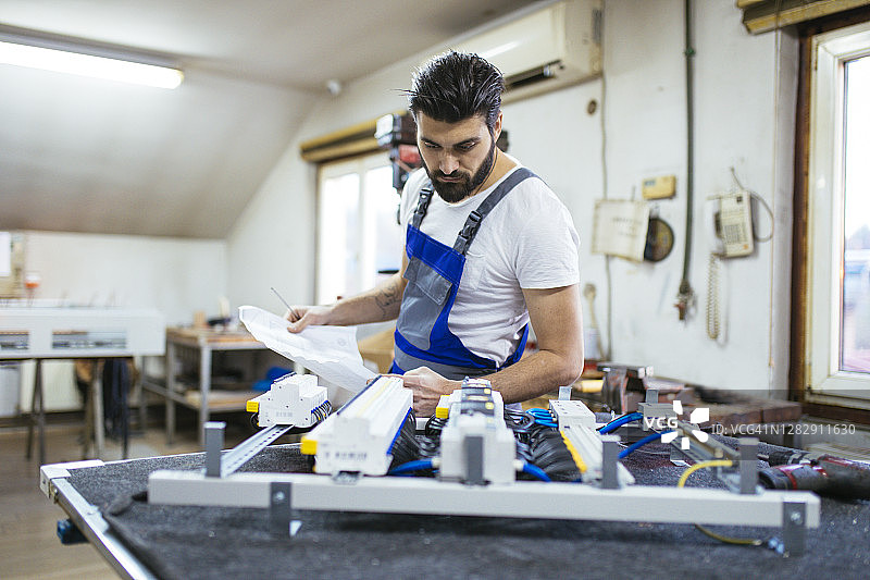 中年电工在车间工作，维修电子元件图片素材