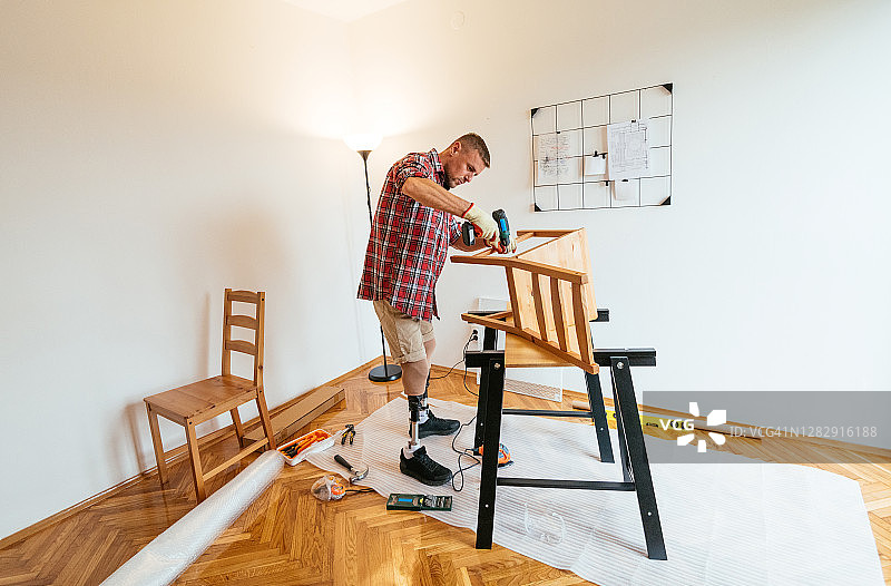 在家组装和修复旧家具的截肢男人图片素材