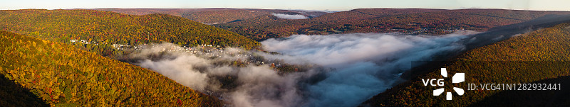 阳光明媚的清晨，低云笼罩着历史名镇吉姆·索普，山谷之间层峦叠嶂，秋色宜人。美国宾夕法尼亚州卡本县波科诺地区。超大型高分辨率航拍拼接全景图。图片素材