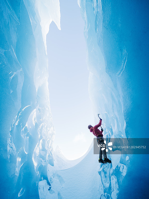 攀冰者攀登垂直的蓝色冰面图片素材
