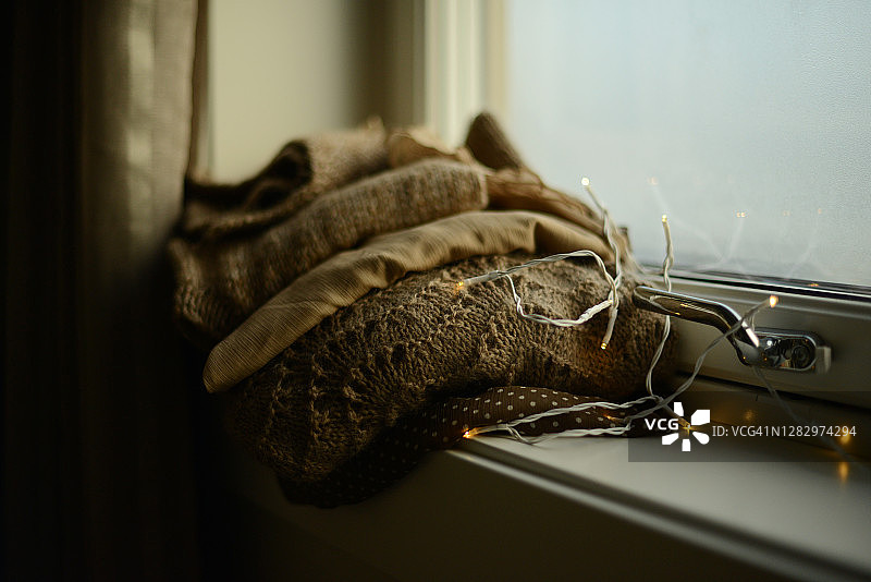 窗台上颜色相配的针织毛衣和丝绸衬衫堆图片素材