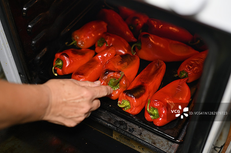 查看烤箱中烤红辣椒的人图片素材