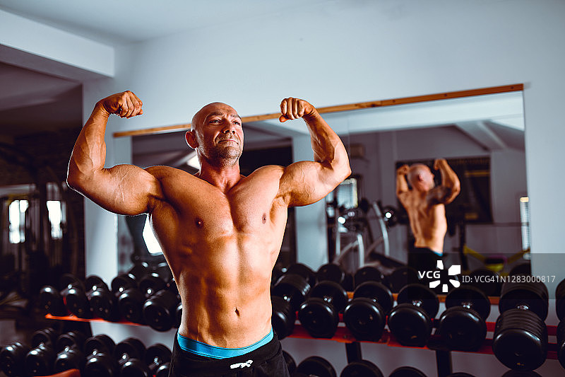 在健身房展示体格和力量的健壮男人图片素材