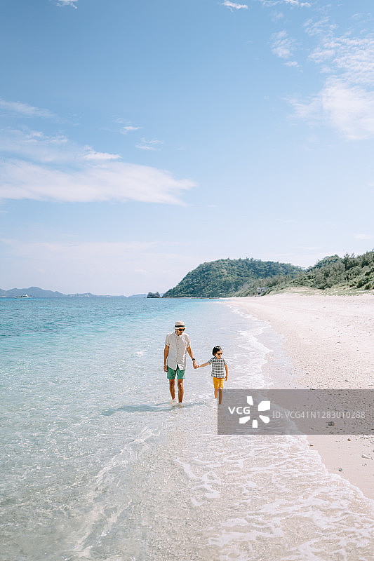 父亲和孩子在冲绳热带海滩上散步图片素材