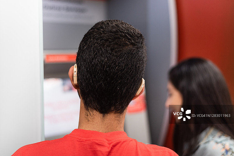 在银行自动柜员机前的失聪年轻人图片素材