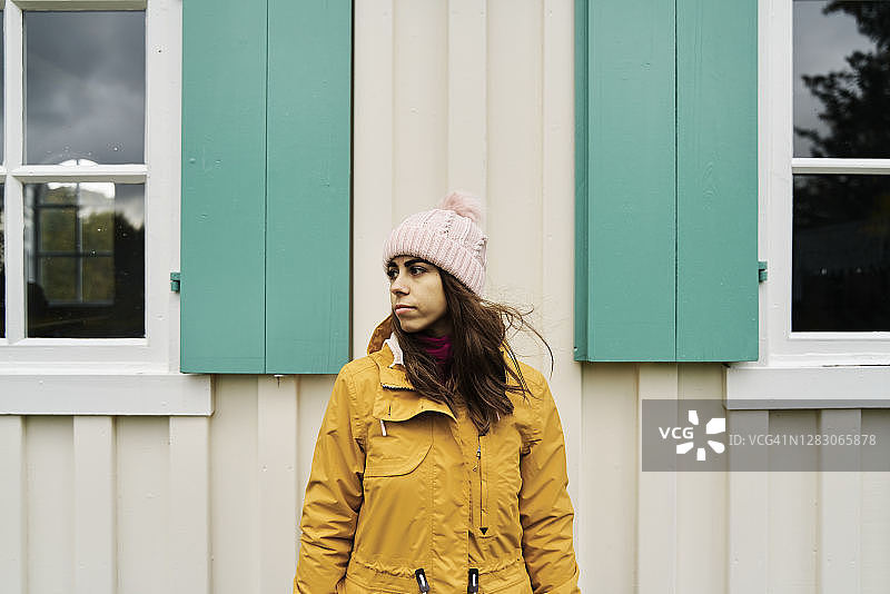 乡间小屋旁沉思的年轻女性旅行者图片素材