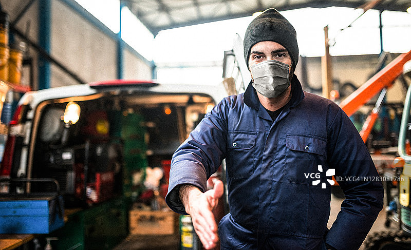 戴口罩站在面包车前的机械师图片素材