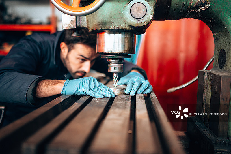 在车间用钻头工作的特纳工人图片素材