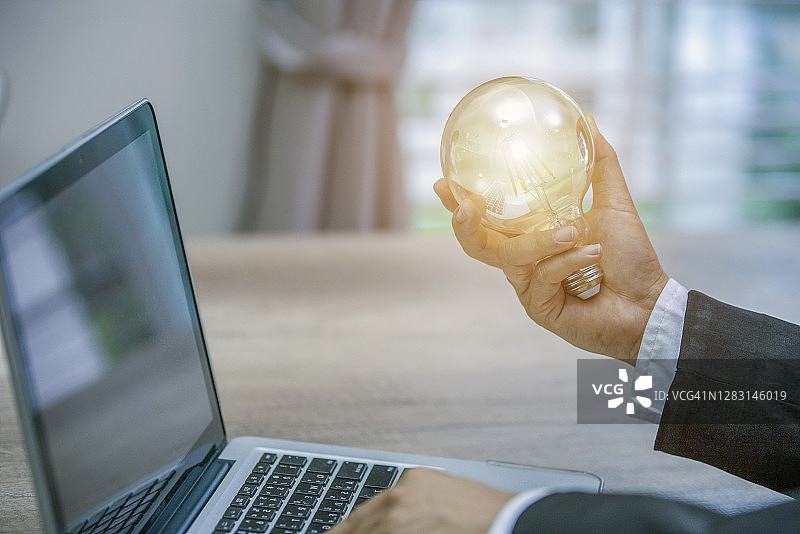 商人拿着发光灯泡的手，创意、创新和灵感概念图片素材