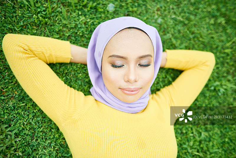 戴着头巾的闭眼亚洲穆斯林年轻女子肖像图片素材