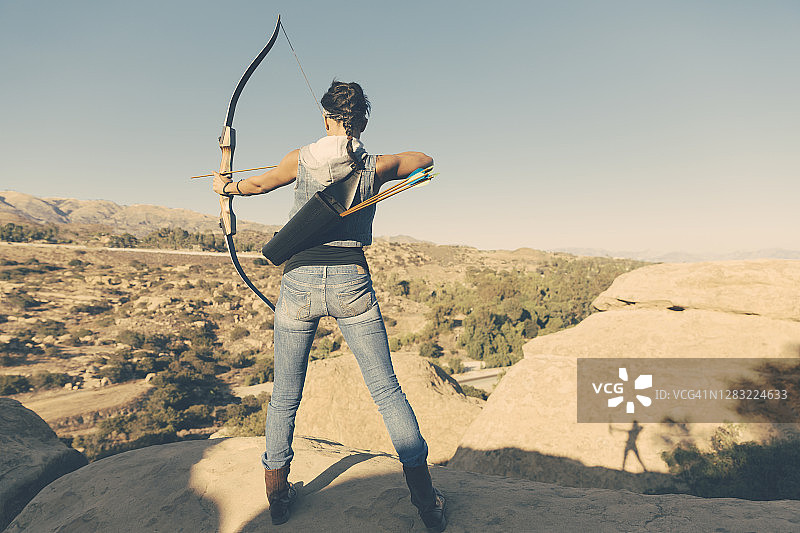 在沙漠中拉弓射箭的年轻女人图片素材