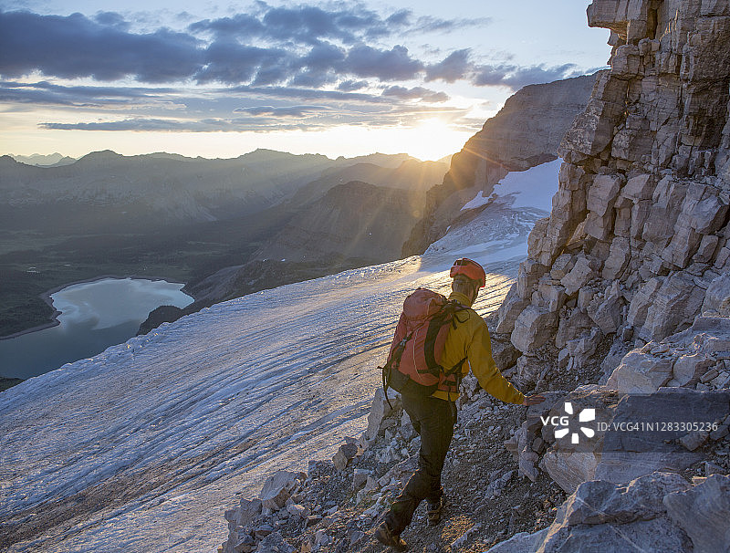 年轻男人在日出时沿着山路徒步旅行图片素材