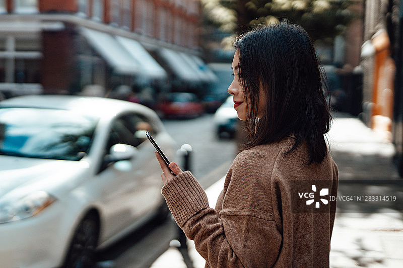 年轻女子在街头用手机等出租车图片素材