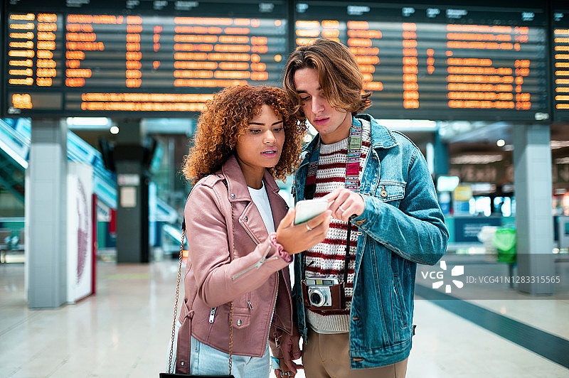 在地铁站看手机的年轻夫妇图片素材