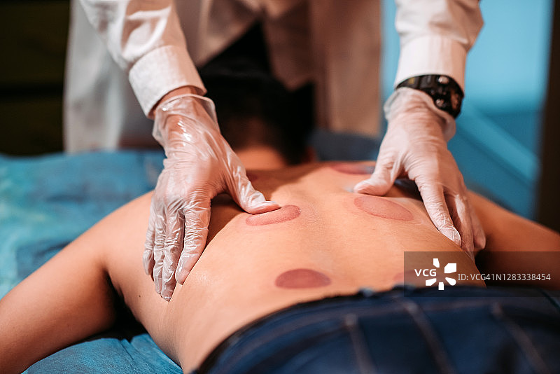 中国男患者在中药店接受刮痧治疗图片素材