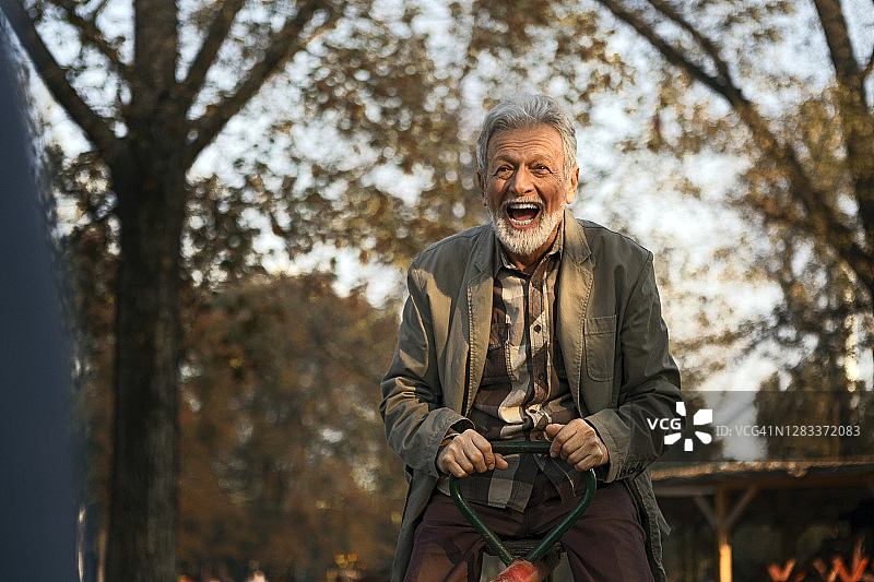 快乐的老年夫妇在操场上玩耍，骑跷跷板图片素材