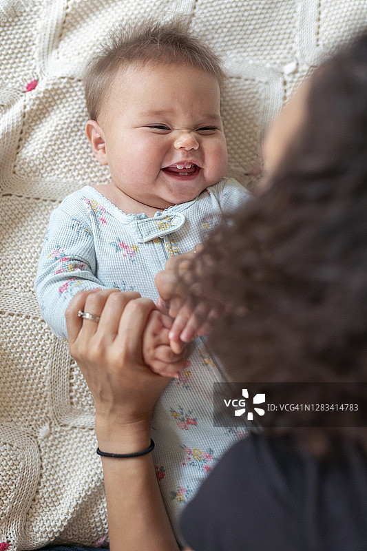 和妈妈玩耍时咯咯笑的可爱混血女婴图片素材