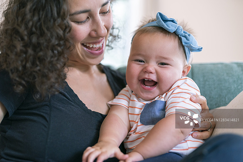 可爱的女宝宝和她慈爱的妈妈玩耍时开怀大笑图片素材