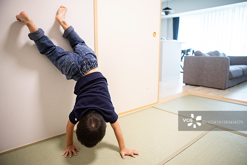男孩在日式房间里靠墙倒立图片素材