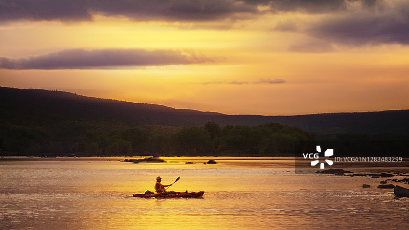 宾夕法尼亚州萨斯奎哈纳河沿岸的橙色日落和皮划艇图片素材