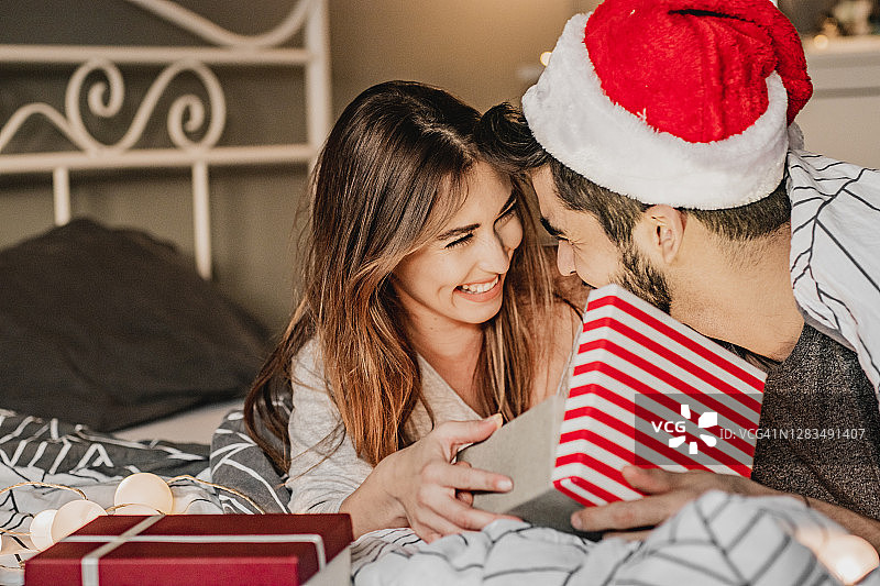 节日期间，情侣在床上互赠圣诞礼物图片素材