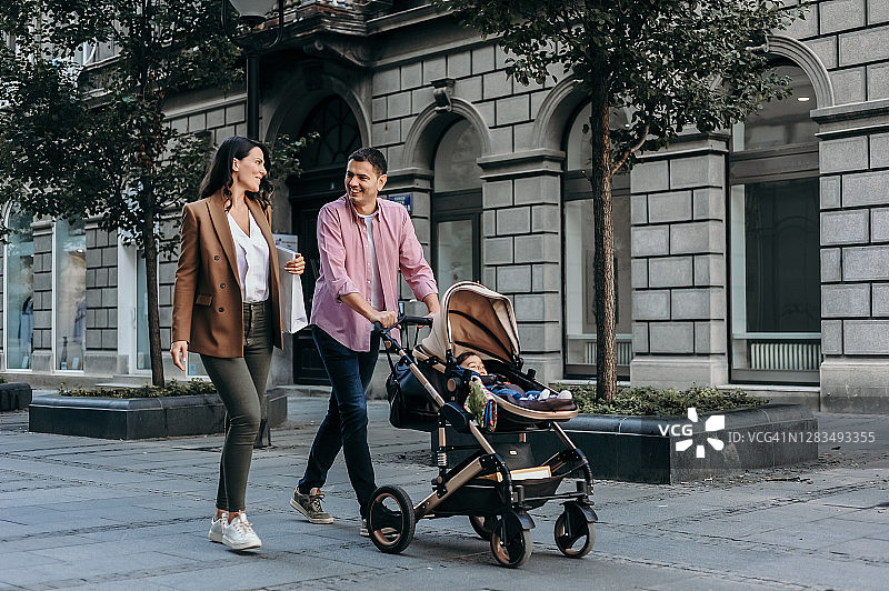 推着婴儿车的家庭在城市中散步图片素材