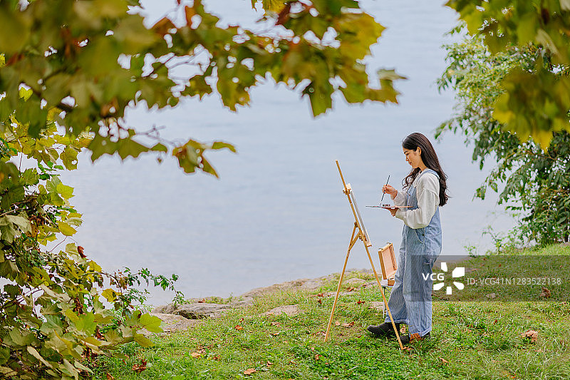 年轻女艺术家在湖边写生图片素材