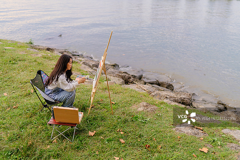 年轻女艺术家在湖边写生图片素材