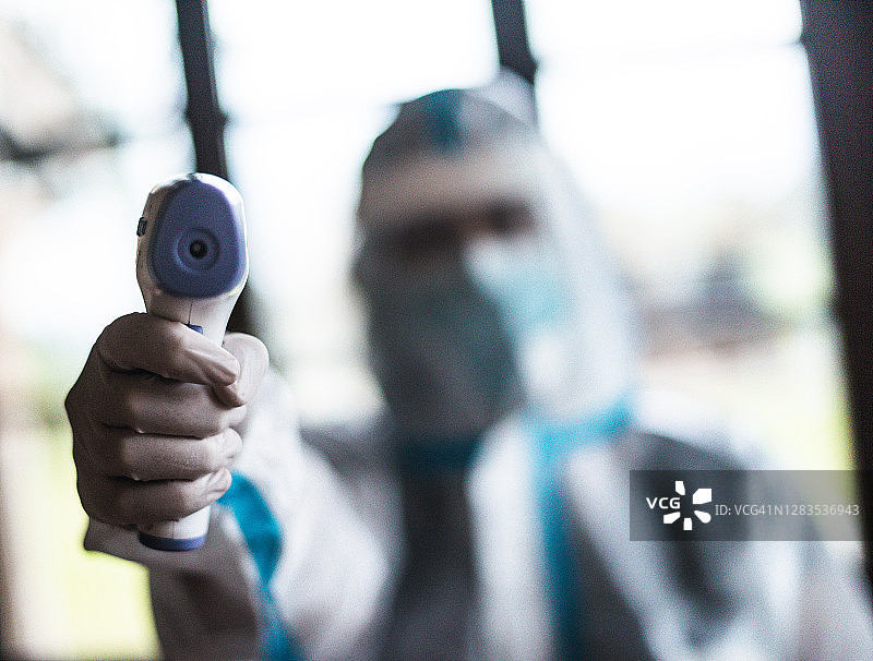 戴着全面防护面罩和使用热扫描仪的医生图片素材