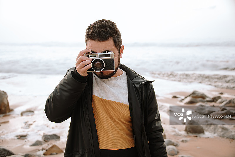 年轻男人用老式胶片相机拍照图片素材