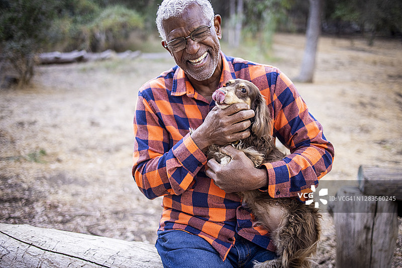 抱着长毛腊肠犬的年长的黑人图片素材