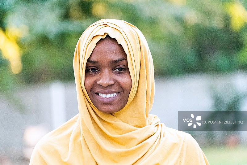 戴着头巾面带微笑看着镜头的年轻黑人穆斯林妇女图片素材