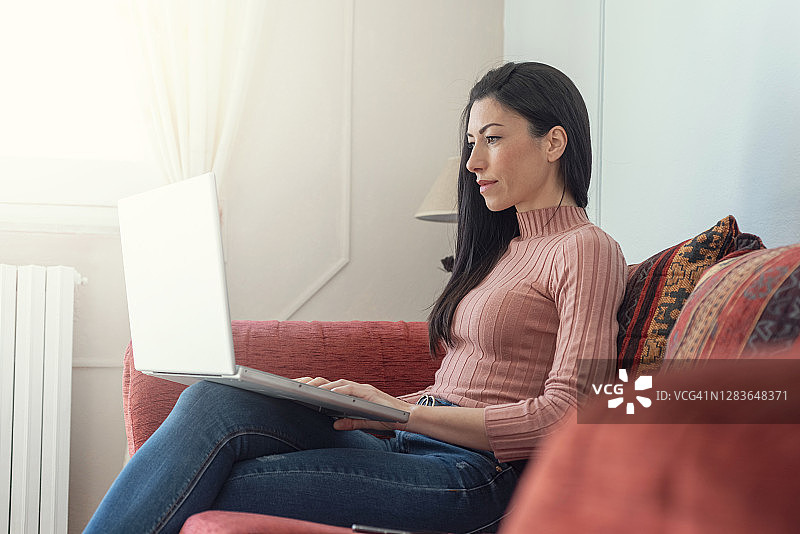 年轻女人在家使用笔记本电脑图片素材