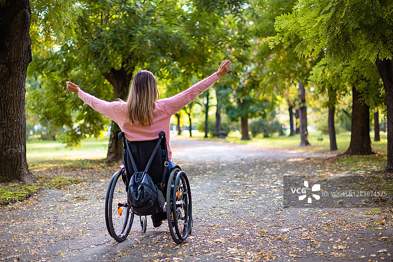 在公园里伸出双臂的年轻残疾女子肖像图片素材